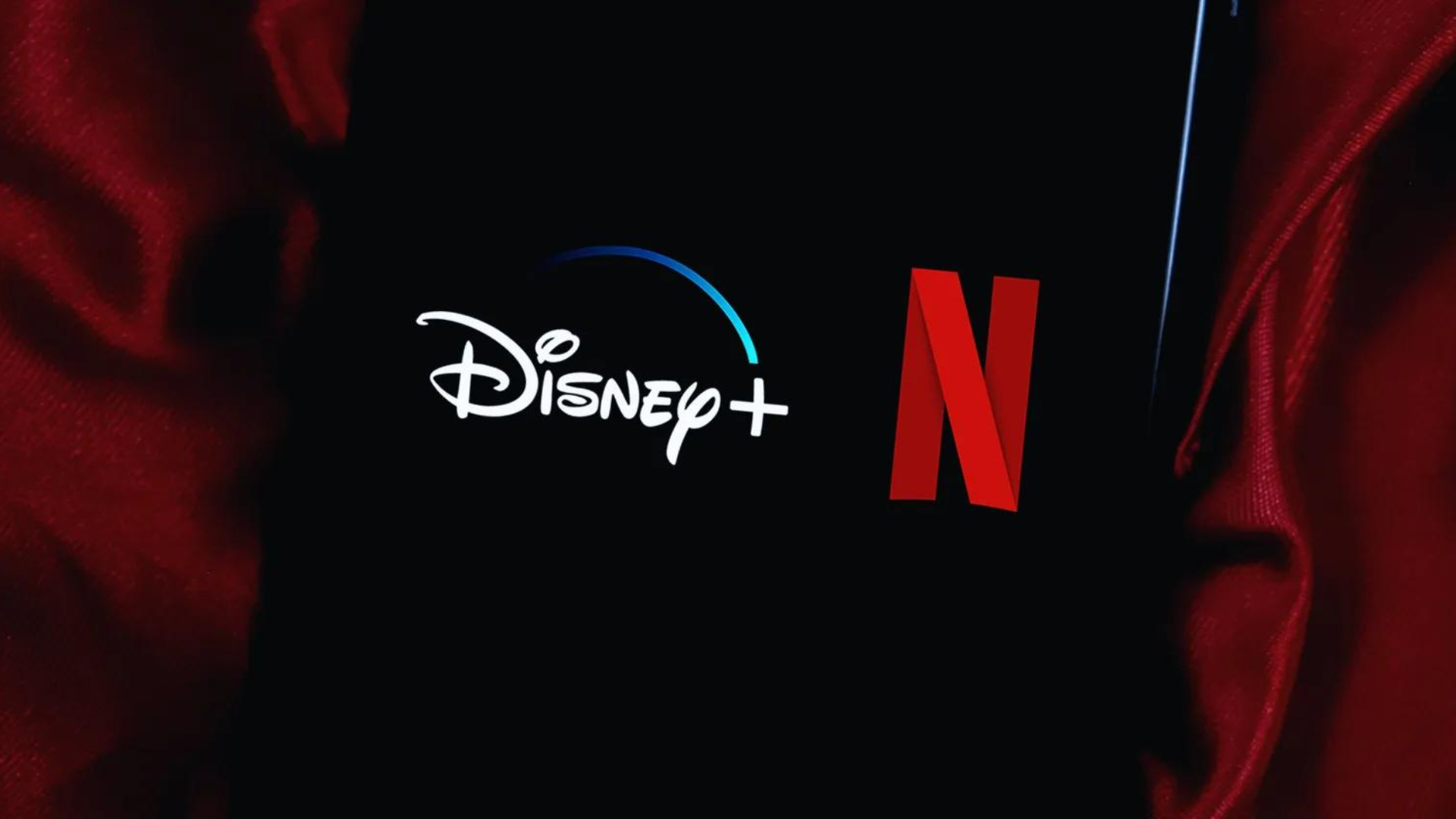 A phone placed on a red silk cloth with netflix and disney logo