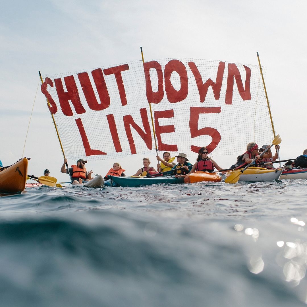 Members of an environmental group aboard a boat show huge cut-out letters that say, ‘shut down Line 5’