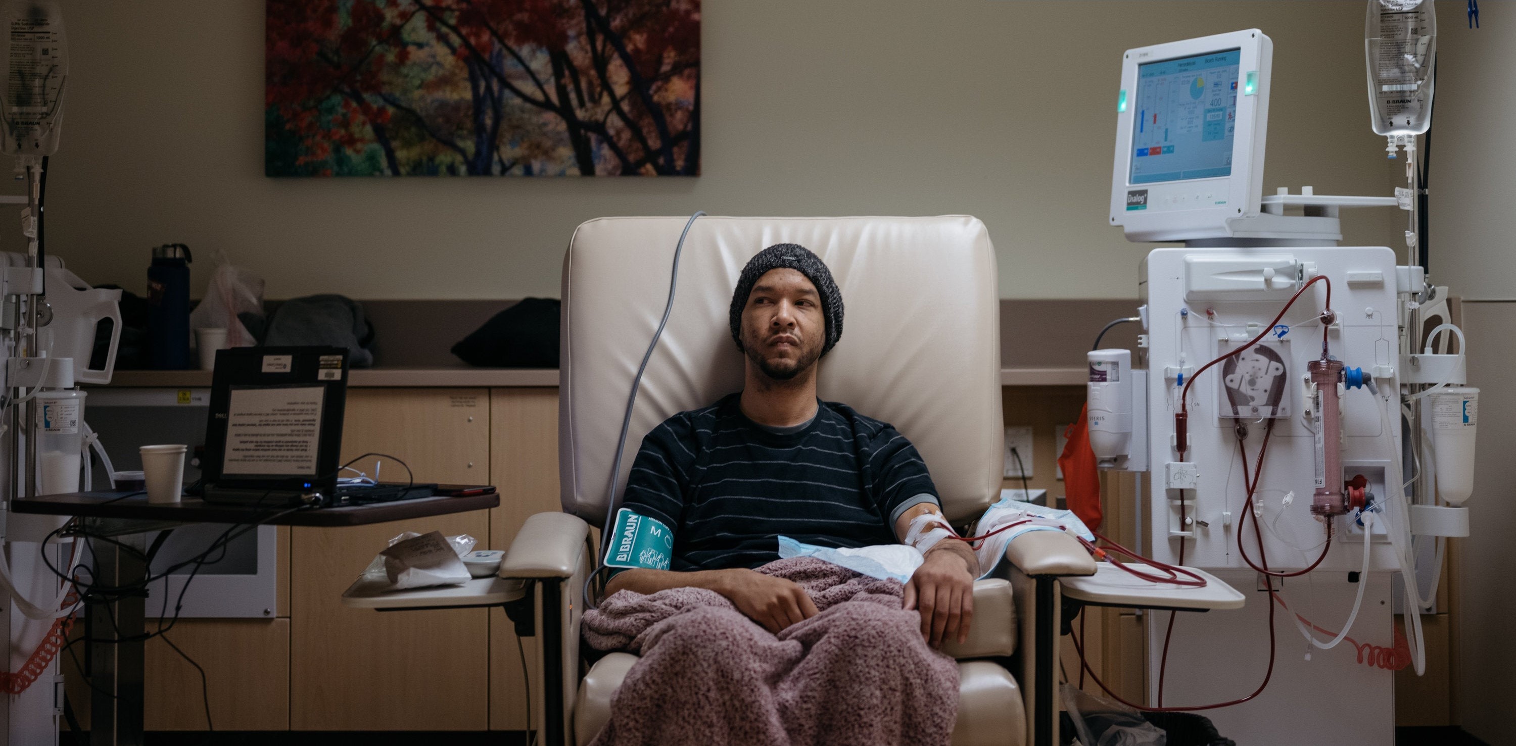Male patient sitting in a big chair with blanket while hooked up to a dialysis machine