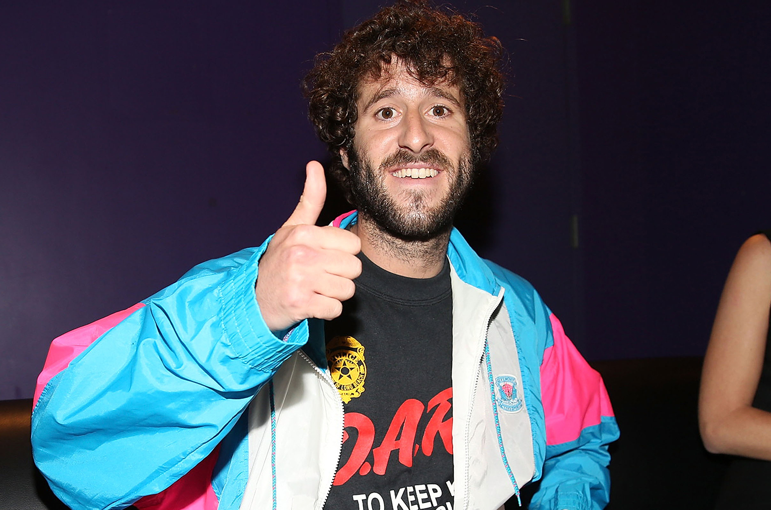 Lil Dicky smiling and doing a like sign in his hand