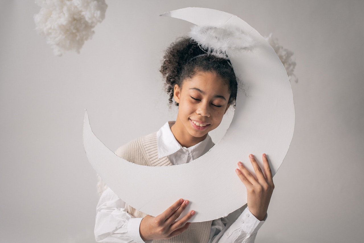 Smiling kid with eyes closed holding handmade moon