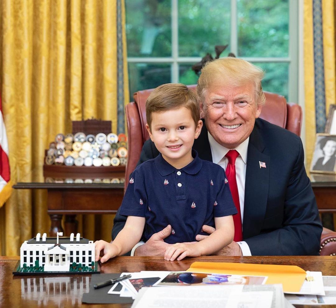 Donald Trump smiles for the camera at the Oval Office with his grandson, Joseph Frederick Kushner, on his lap