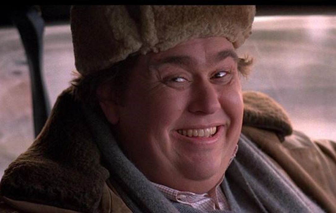 John Candy sitting and smiling in car