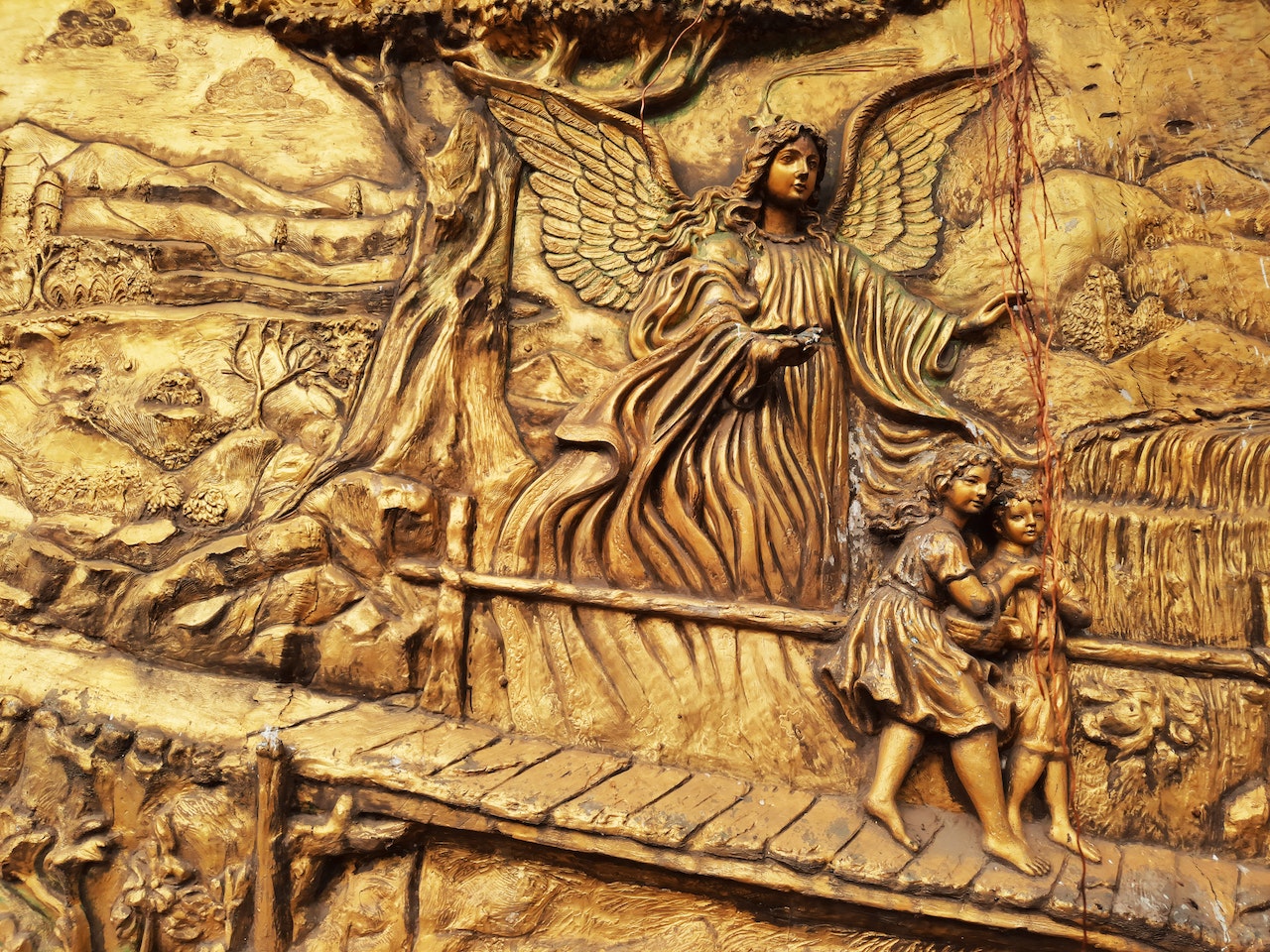 A sculpture of an angel guiding two children