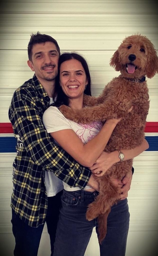 Andrew Schulz holding his wife and dog