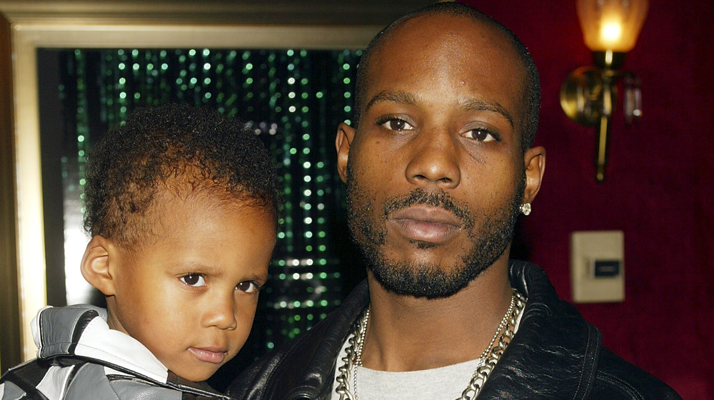 DMX wearing a black leather jacket and holding Tacoma Simmons as as kid