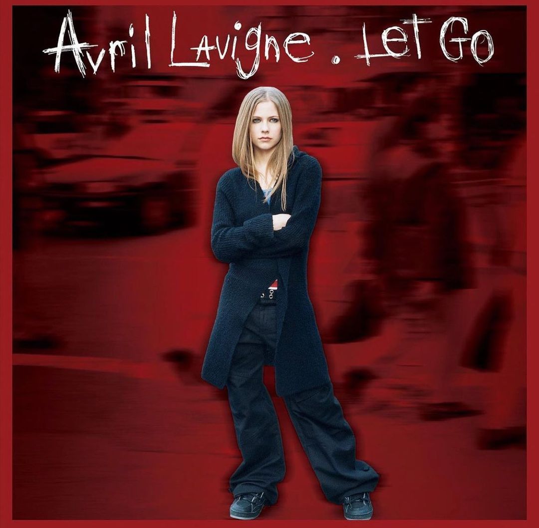 Avril Lavigne in blazer and baggy pants and with her hands crossed