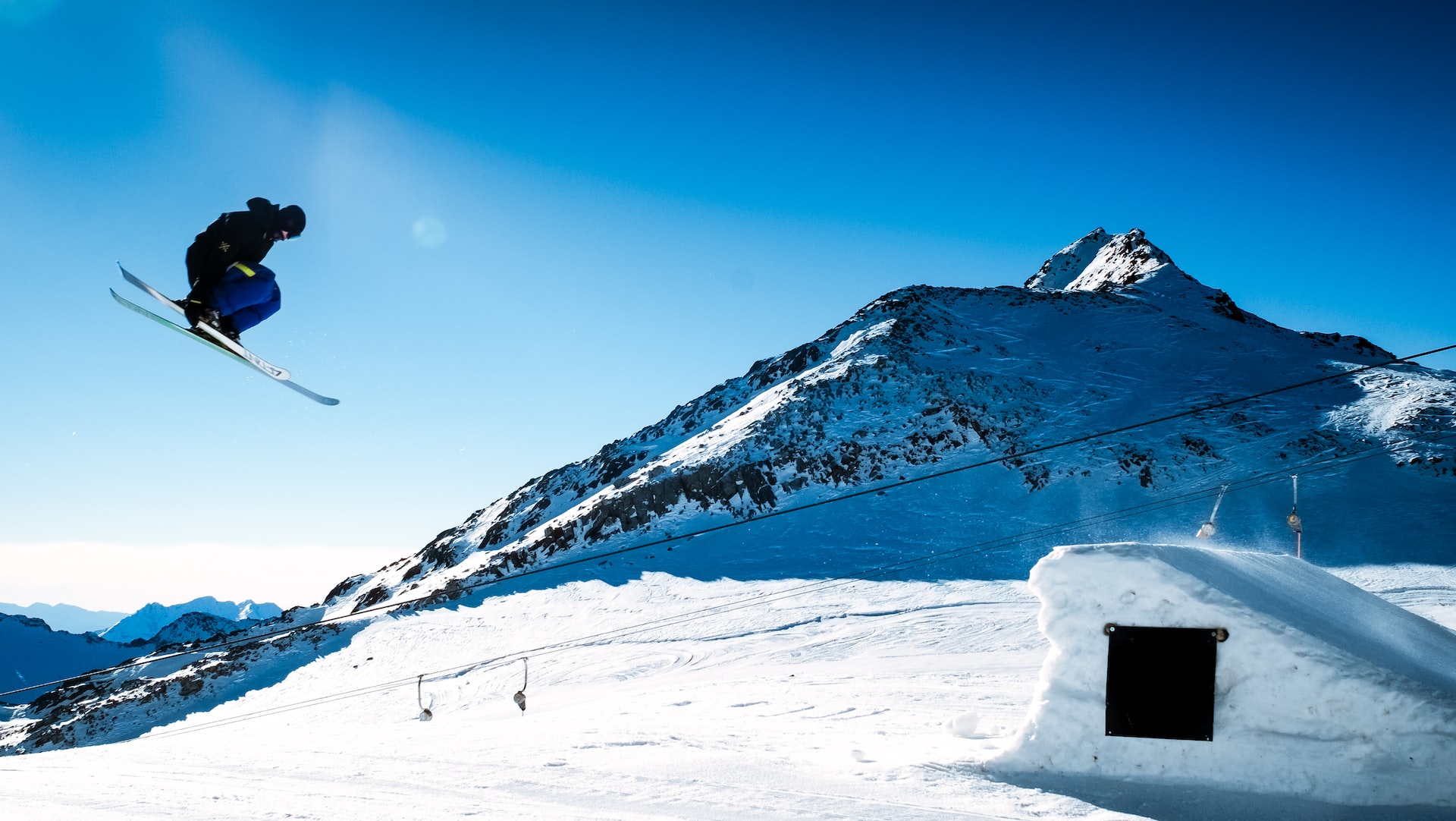 A male skier in midair bends his legs at the Stubai Glacier ski resort in Austria