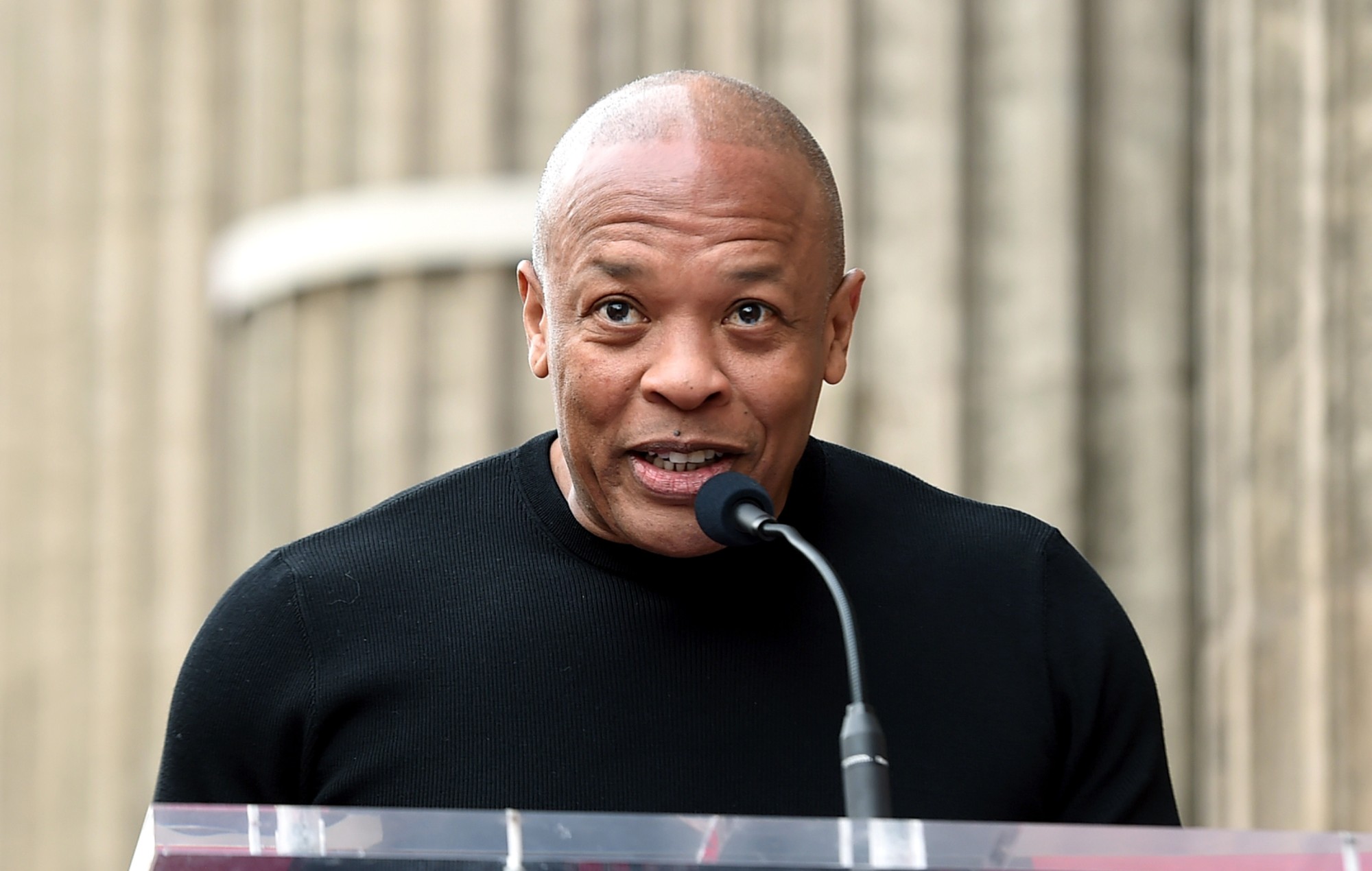 Dr. Dre speaking in front of a mic wearing black shirt