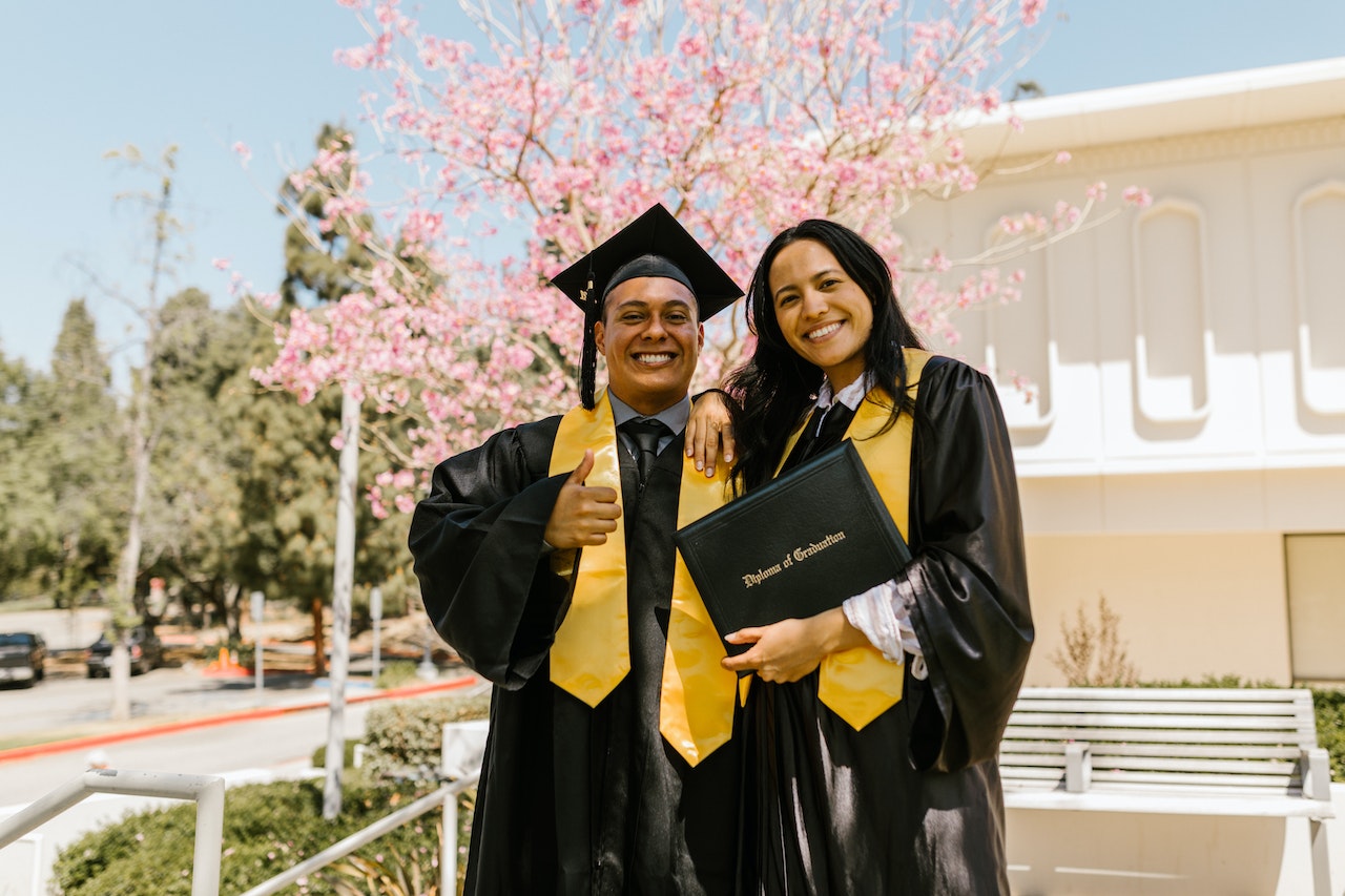 Man and Woman Wearing Graduation Gowns Smiling Together
