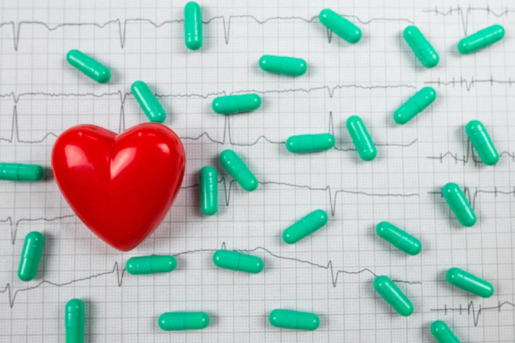 Red heart and green pills with cardiogram background