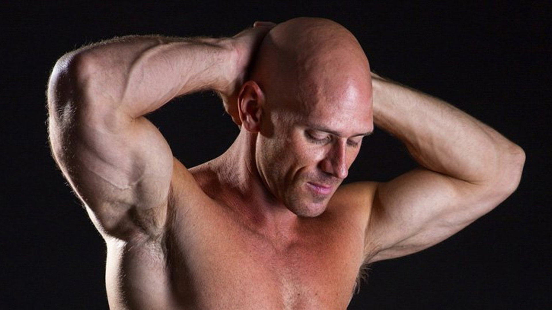 Johnny Sins without shirt with his hands on his head
