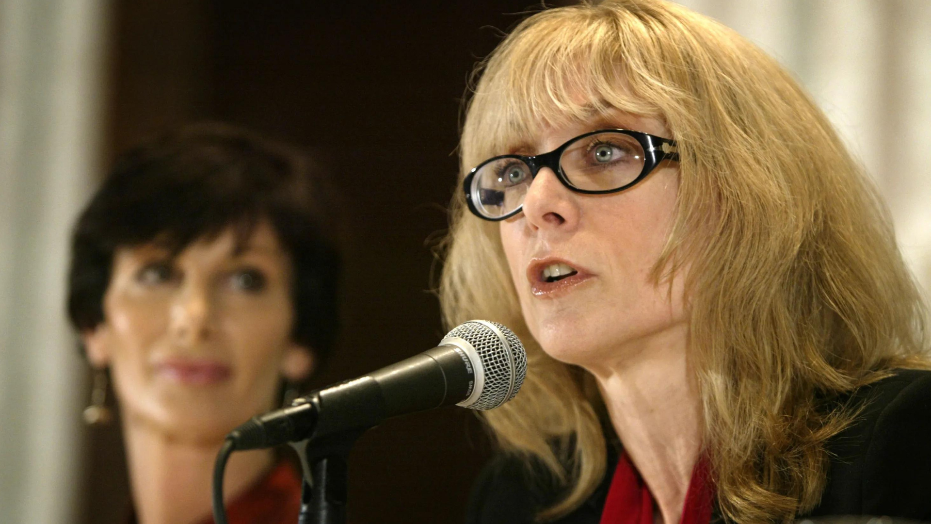  Nina Hartley speaking in front of a microphone