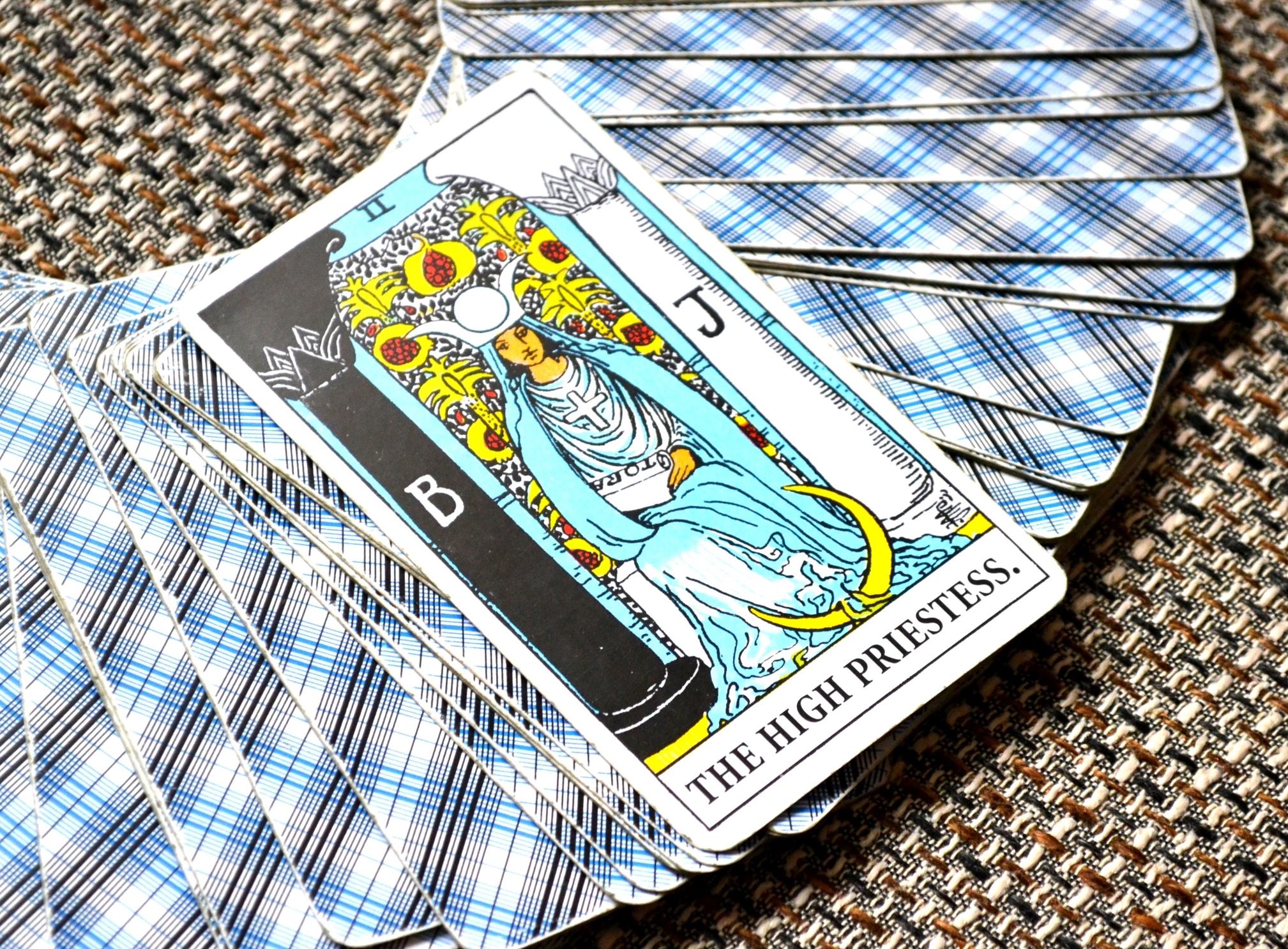 A deck of tarot cards with the High Priestess card on top facing upright