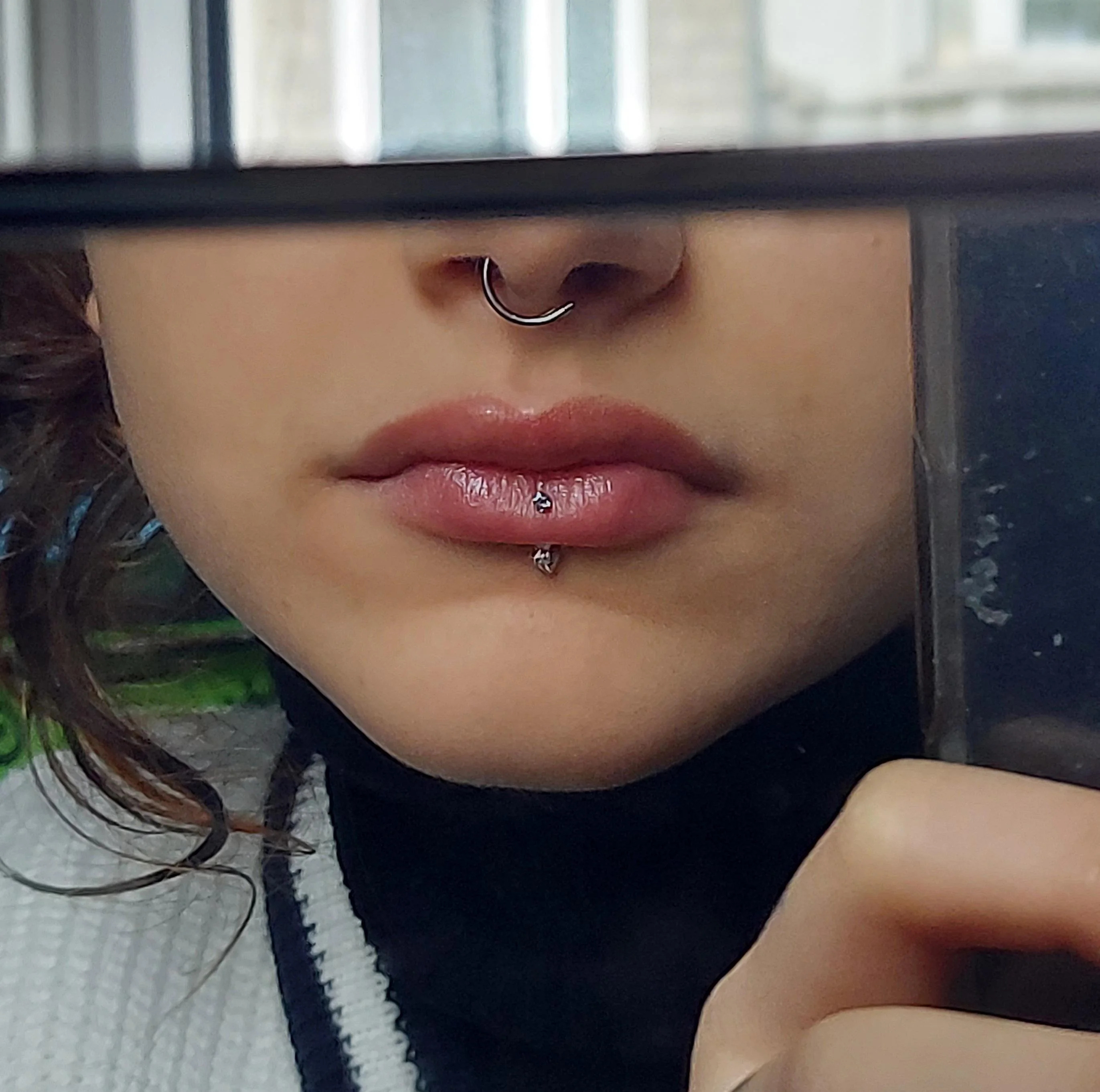 A  woman wearing a cardigan with vertical labret piercing