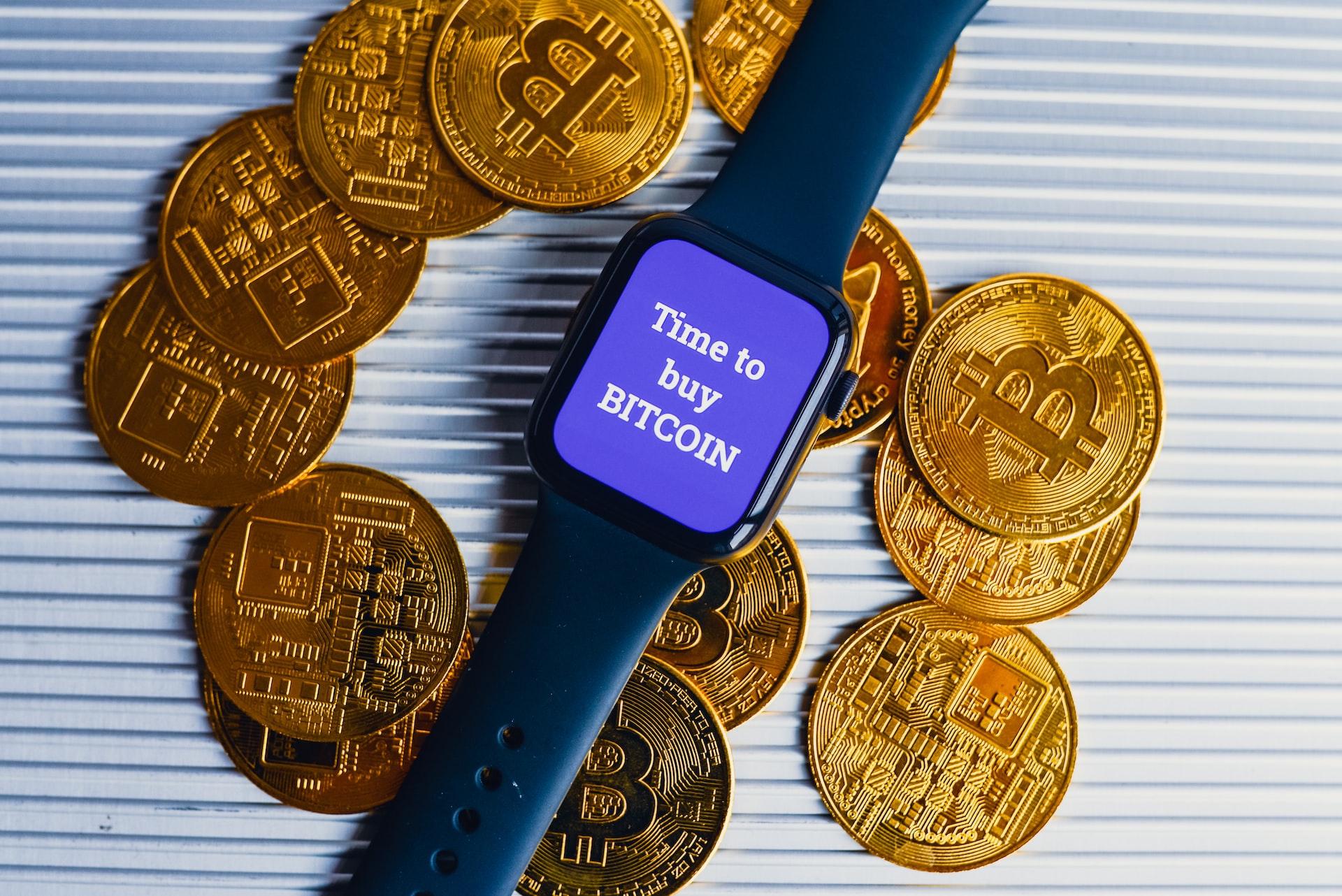 A blue wristwatch with a face that says ‘time to but Bitcoin’ with 13 pieces of bitcoins around it