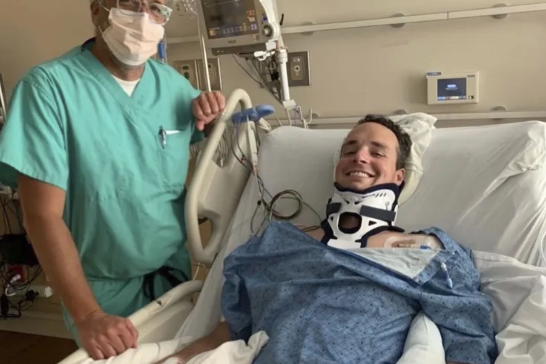 Spencer Brown is laying on a bed, wearing a neck brace, and his doctor on his side