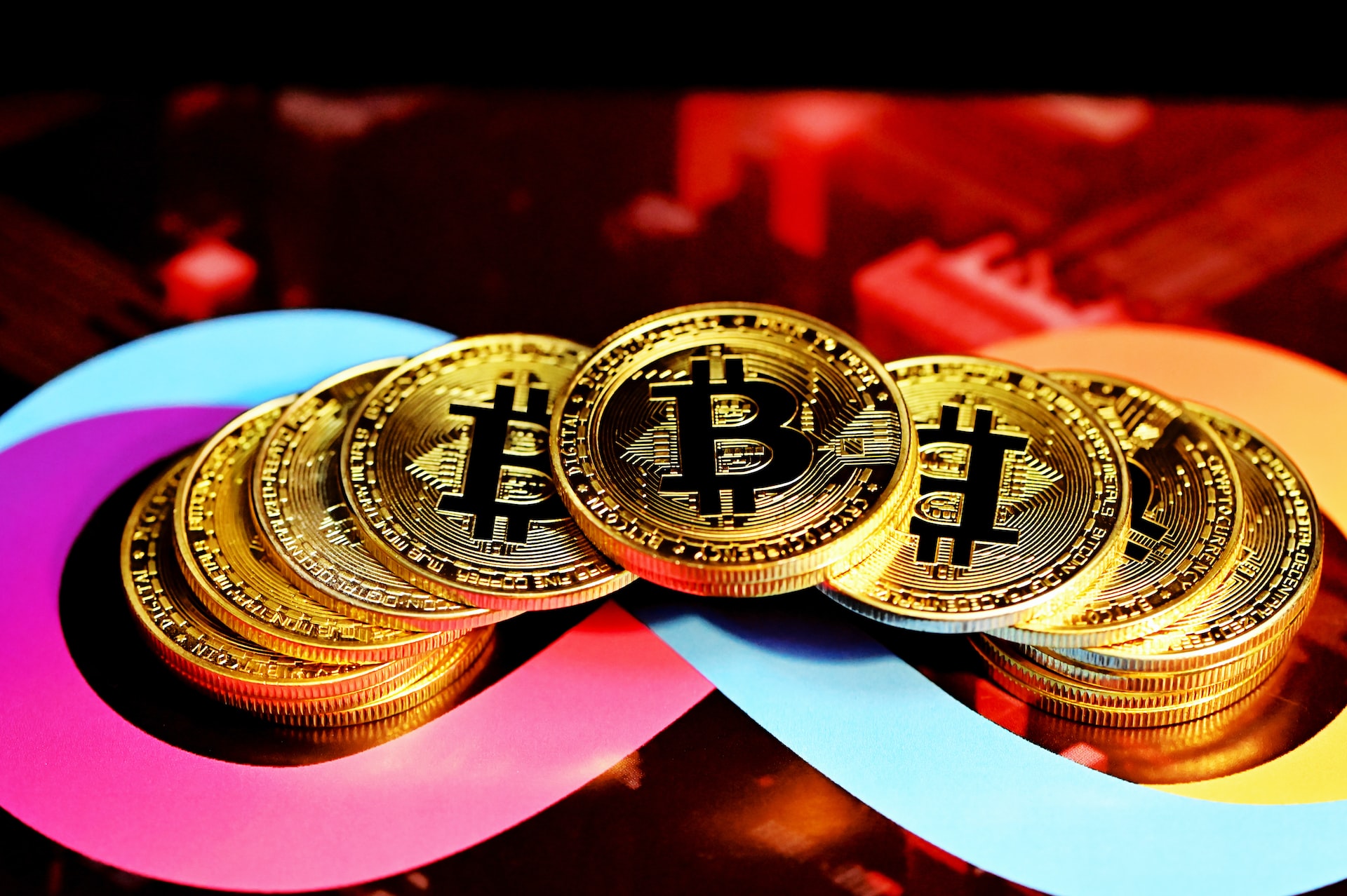 14 pieces of gold bitcoins stacked up within an infinite loop symbol in pink, light blue and yellow