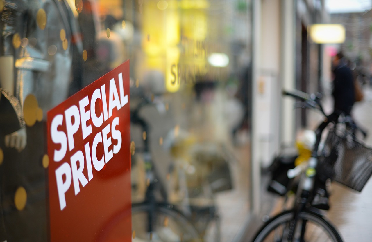 A bicycle parked outside a store, with ‘special prices’ sign in white and in red background on its glass panel