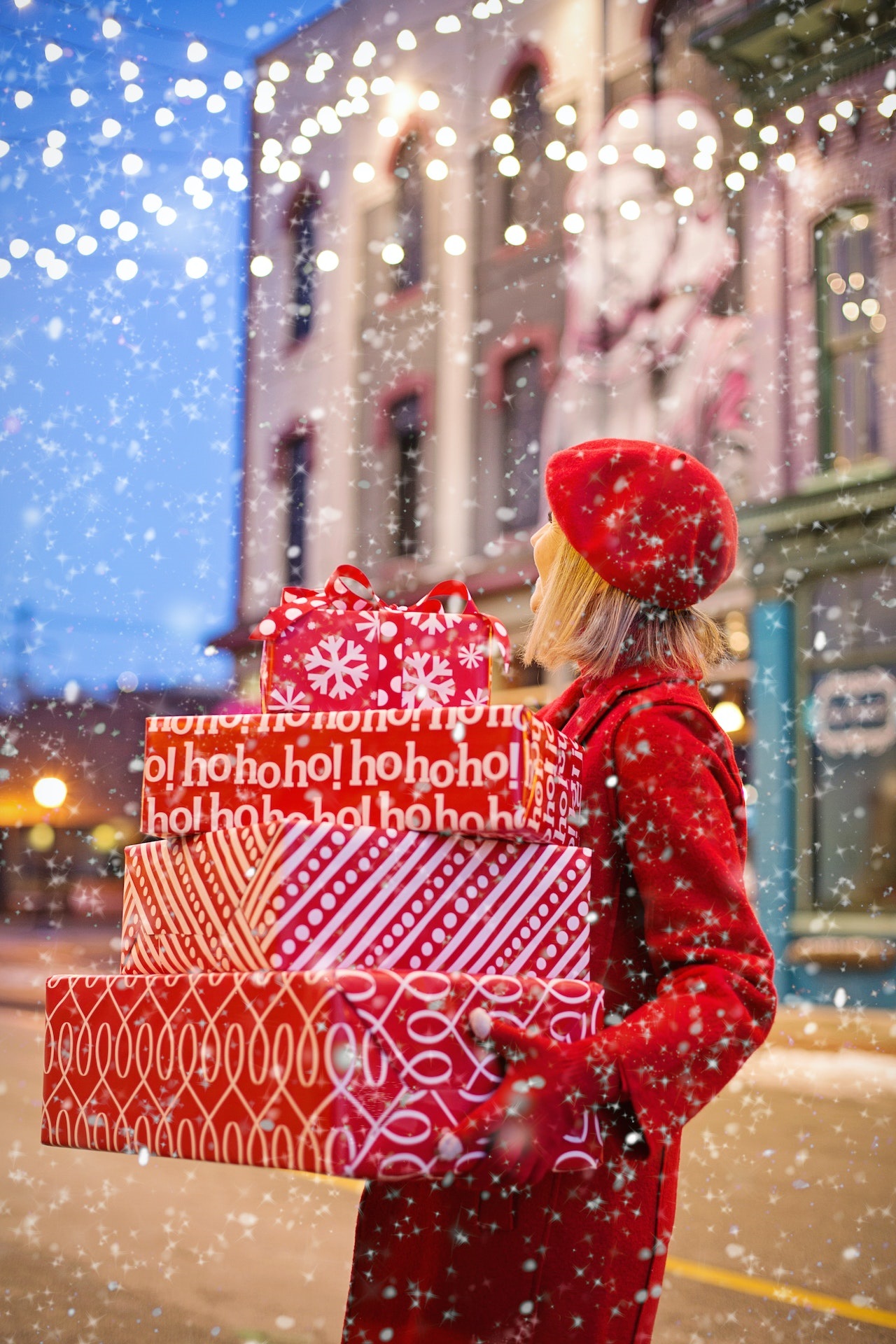 Woman in red beret and coat out on the street holding three Christmas presents boxes in red wrapper