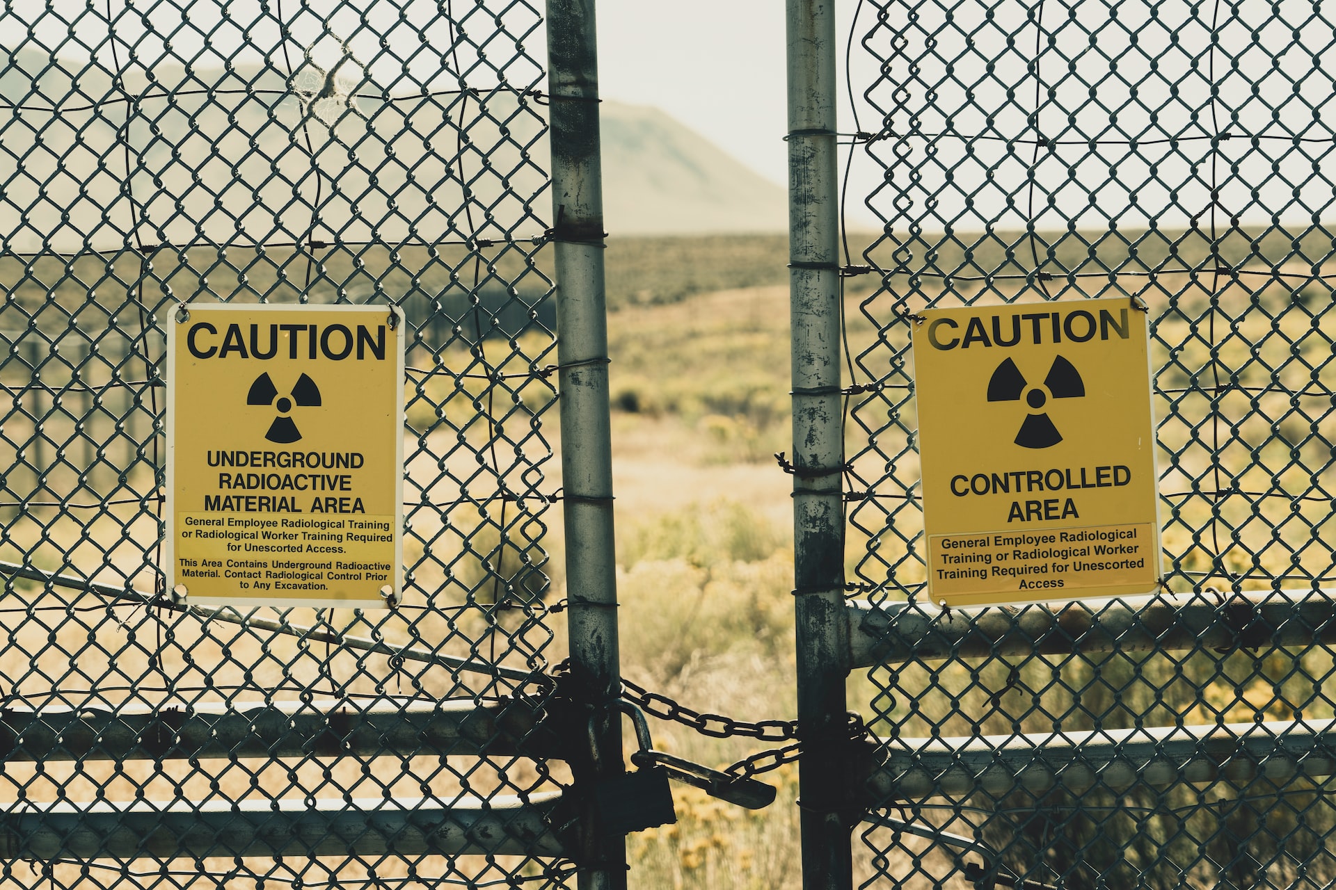 A padlocked gate with a caution sign for a radioactive place underground