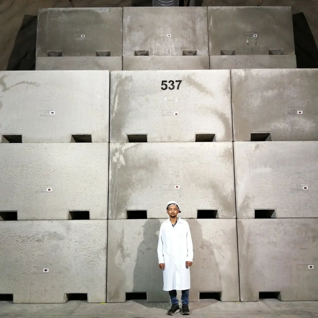 A male in white lab gown in front of massive concrete nuclear waste storages at Bataapati in Tolna, Hungary