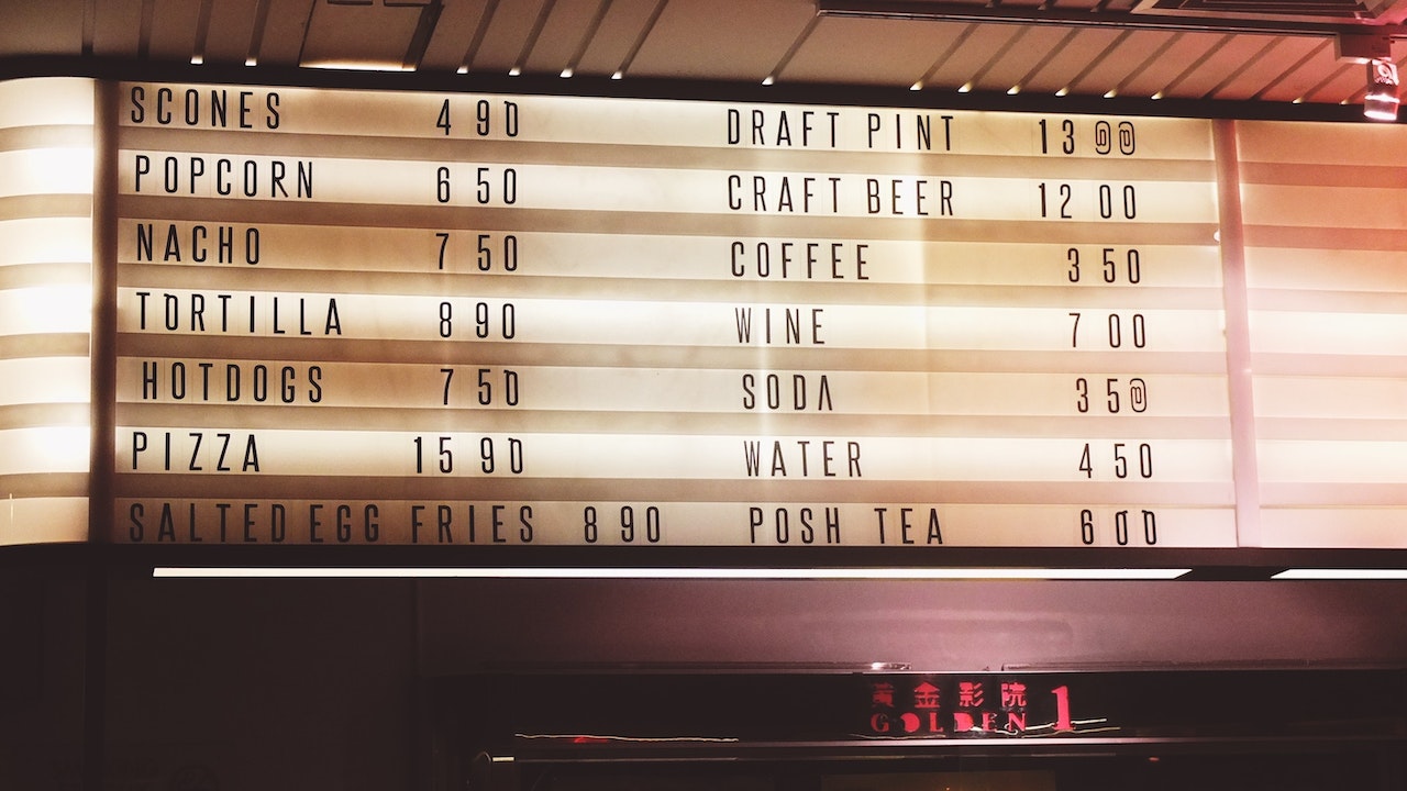 A diner menu board price for snacks like popcorn, nacho and tortilla and beverages like beer, soda and coffee