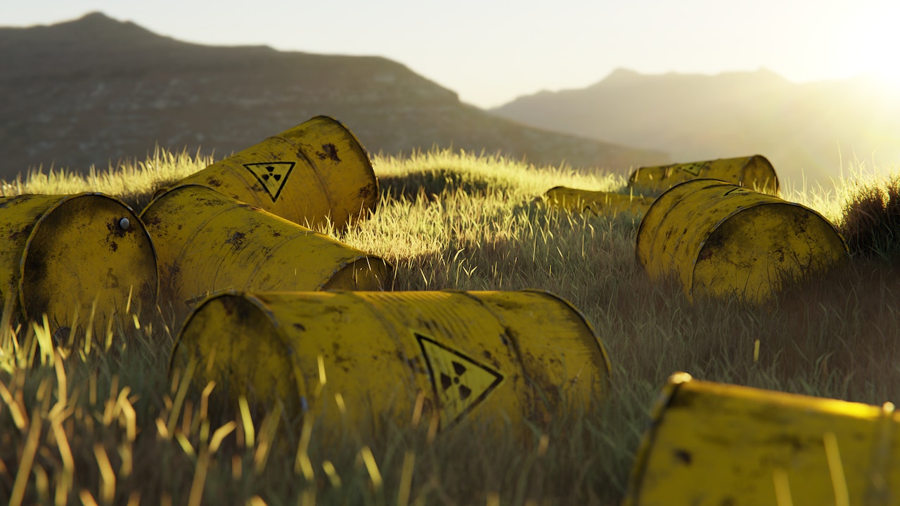 Rusting yellow-painted nuclear waste containers with radioactive sign lying on the grass