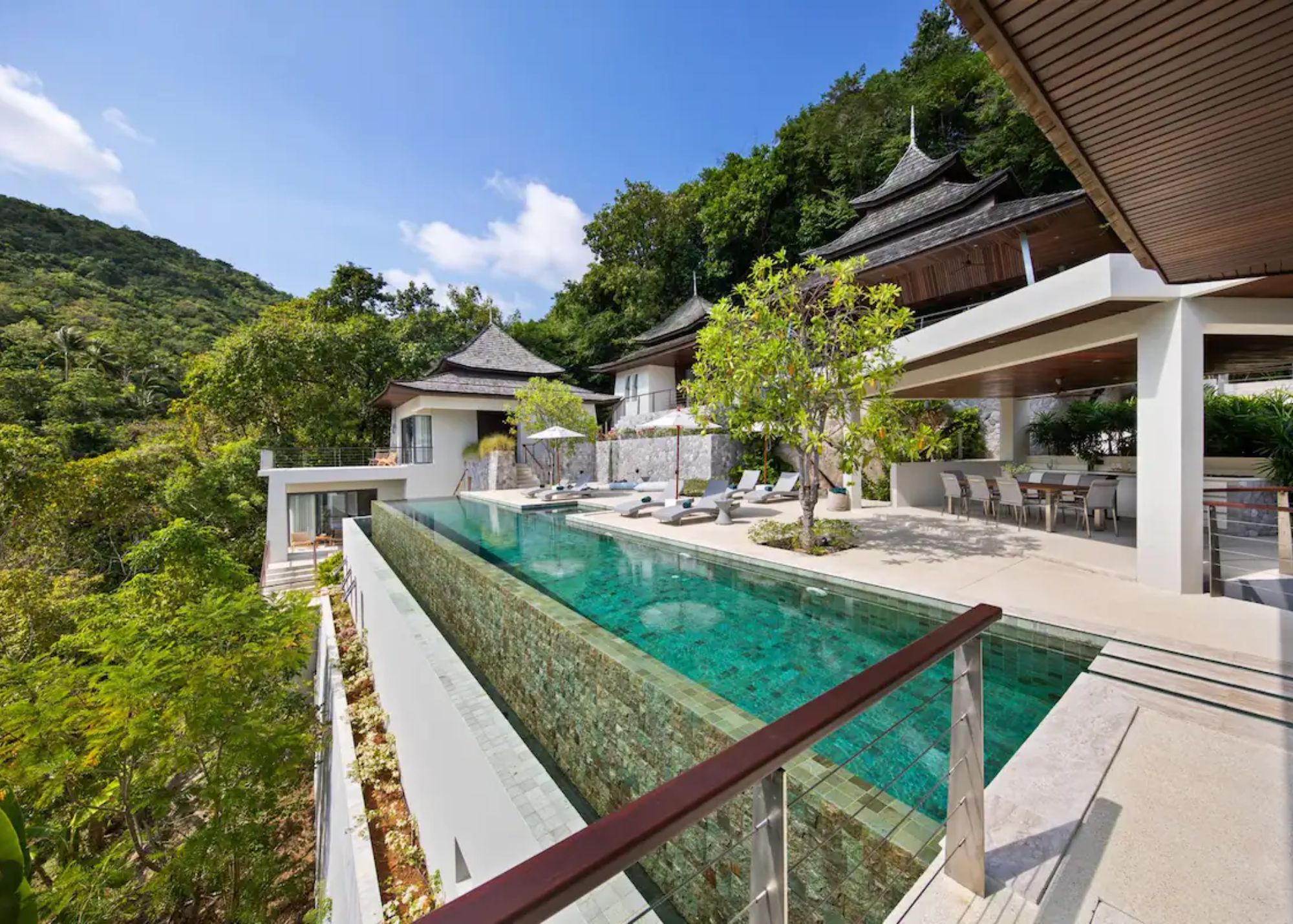 Lap pool with expansive terrace, waterfall, and covered open-air day kitchen
