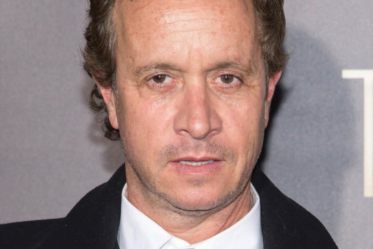 Pauly Shore's face as he's wearing a white t-shirt and a black coat