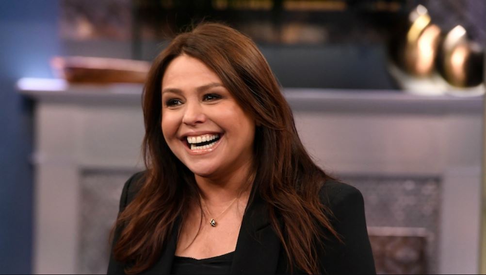 Rachael Ray wearing a black suit with a smile on her face