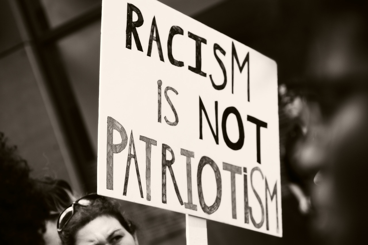 Female anti-apartheid protester holding a placard with the words ‘Racism is not patriotism’ in uppercase form