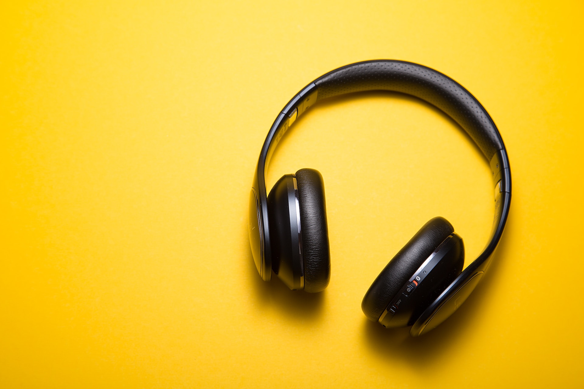 A black headphone on a yellow background