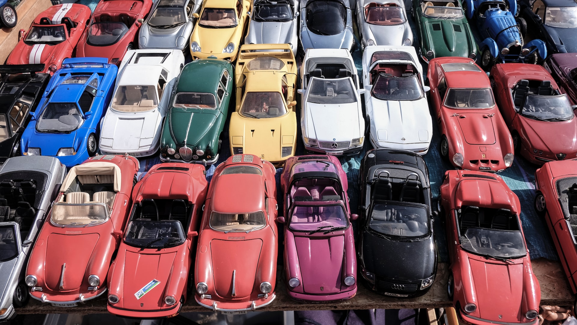 Rows of colorful cars, some of which are top down cars, parked closely together