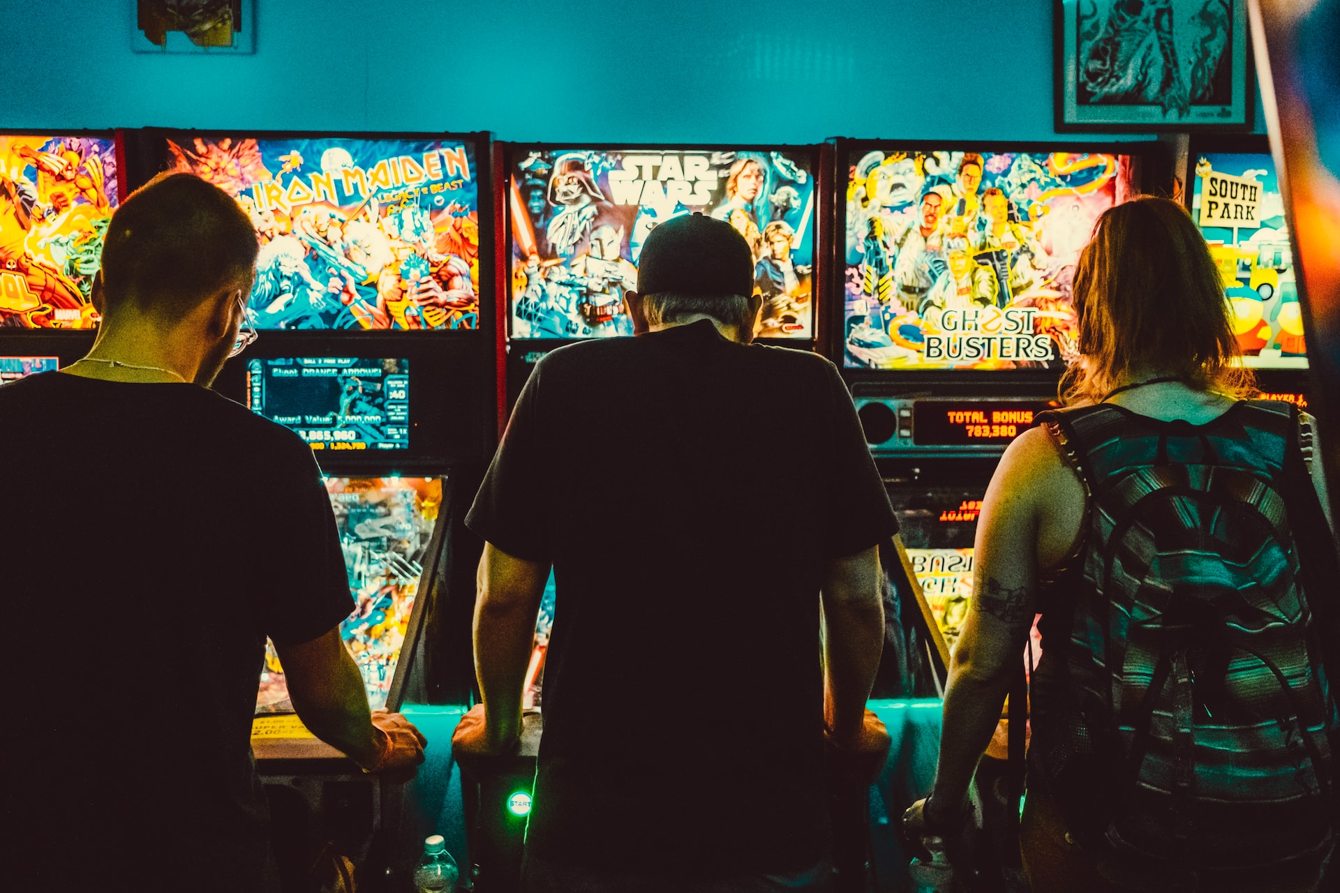 Three people standing before slot machine games in a casino