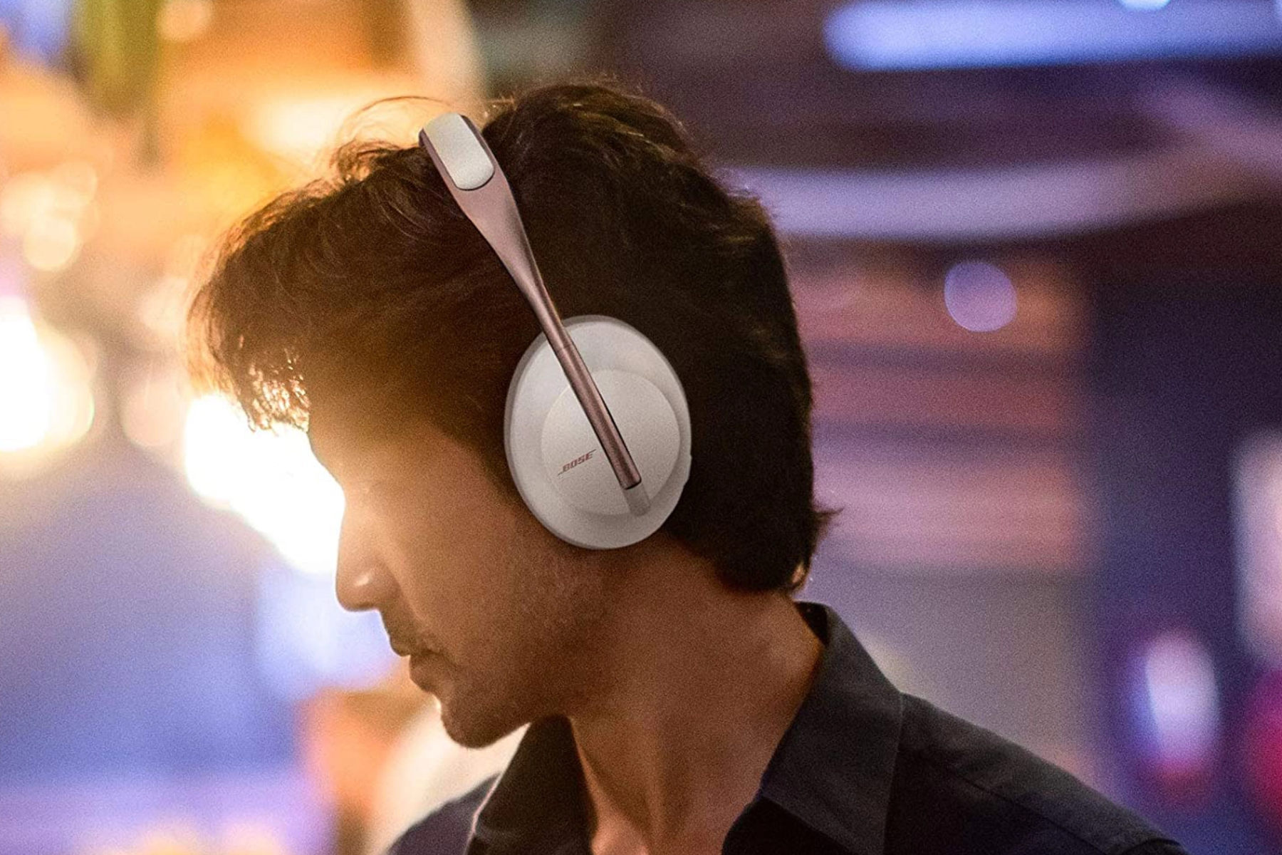 A man poses from the side while wearing Bose headphones