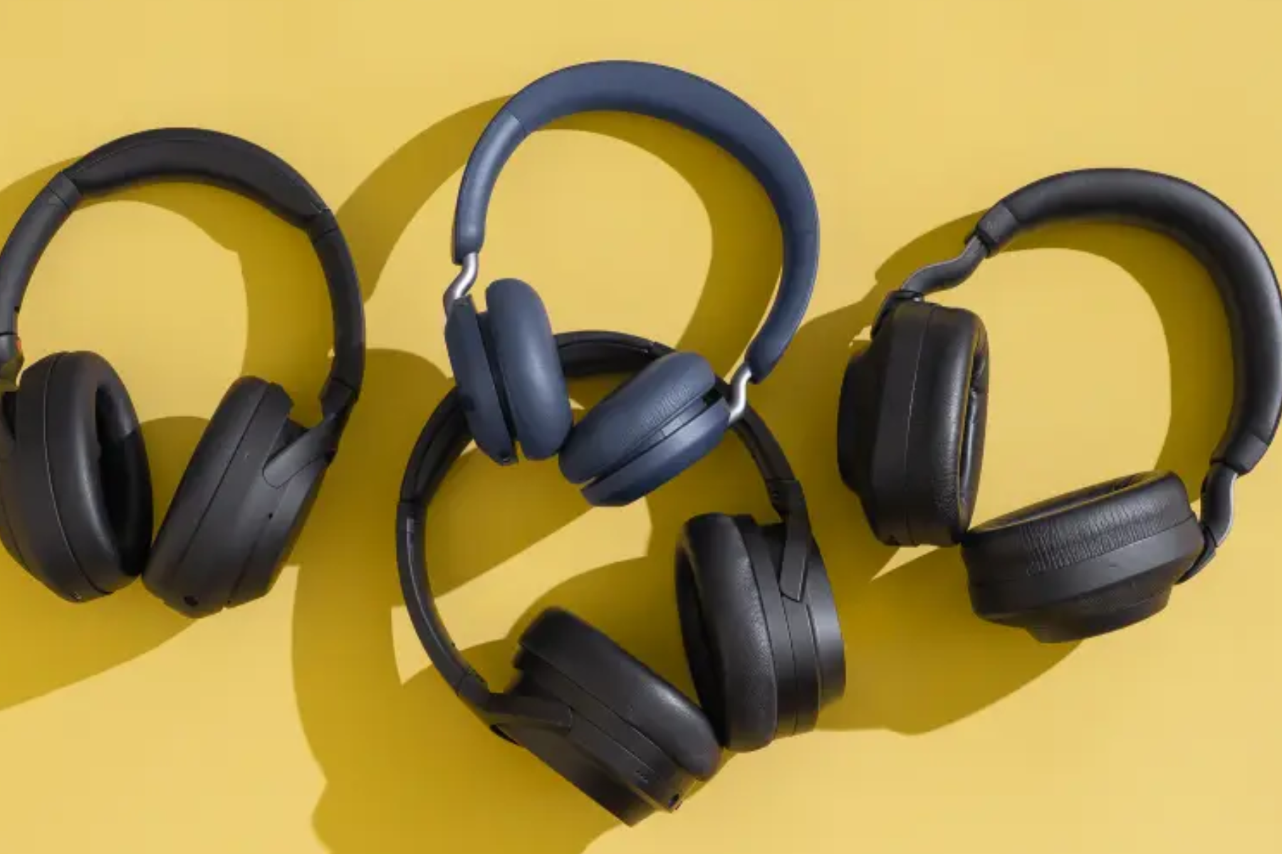 Four Bluetooth headphones on a yellow wall