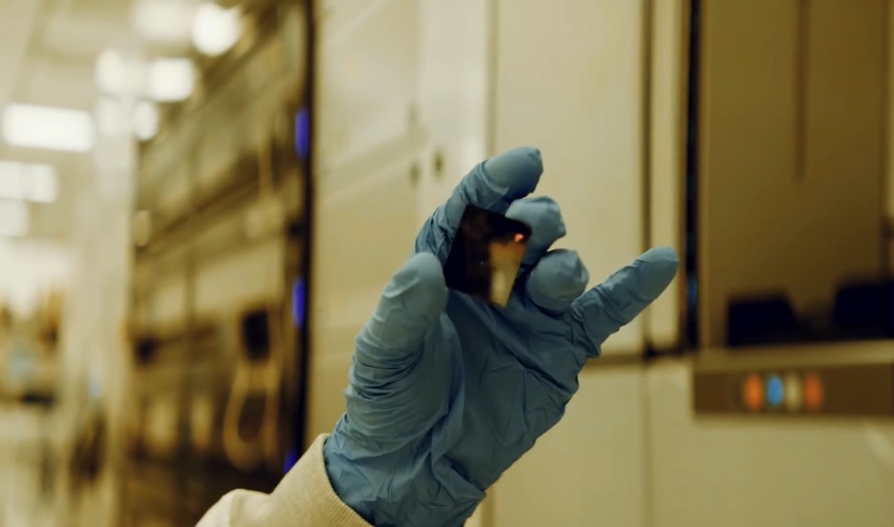 An IBM 2nm transistor held by a gloved hand inside an IBM facility