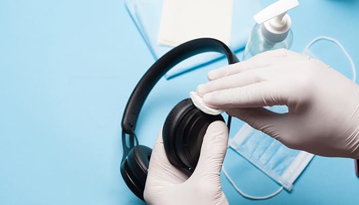 A person wearing gloves is cleaning a headphone