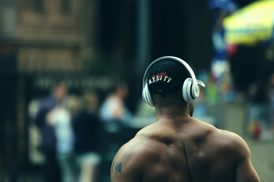 Topless Man Wearing His Beats Headphones Over His Black Cap In The Gym