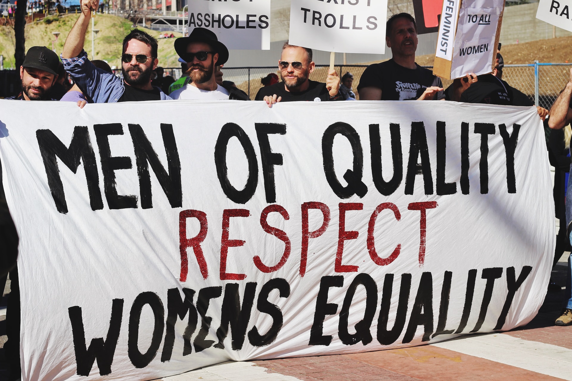 Male protesters on the street holding a white banner saying ‘men of quality  respect women’s equality’