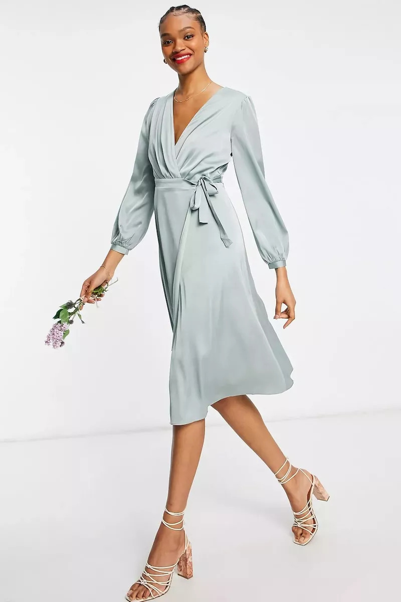 A Bridesmaid Wearing A TFNC Long Sleeve Sateen Midi Dress And Holding A Flower
