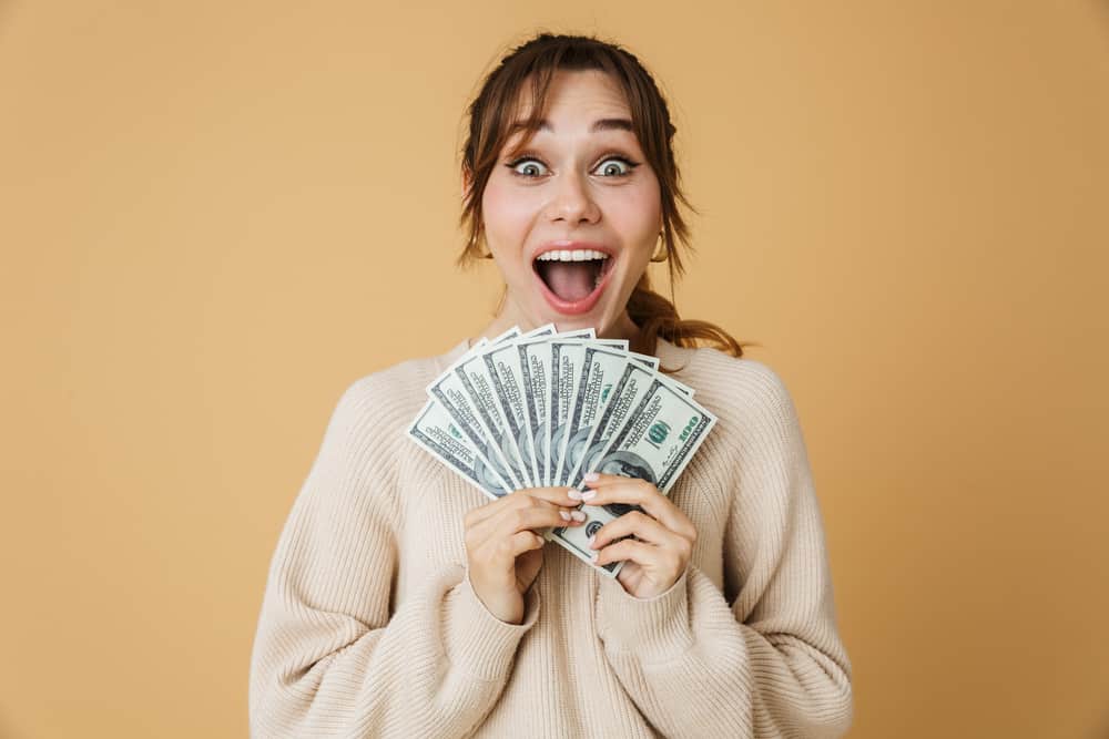 A girl is very happy while holding dollars