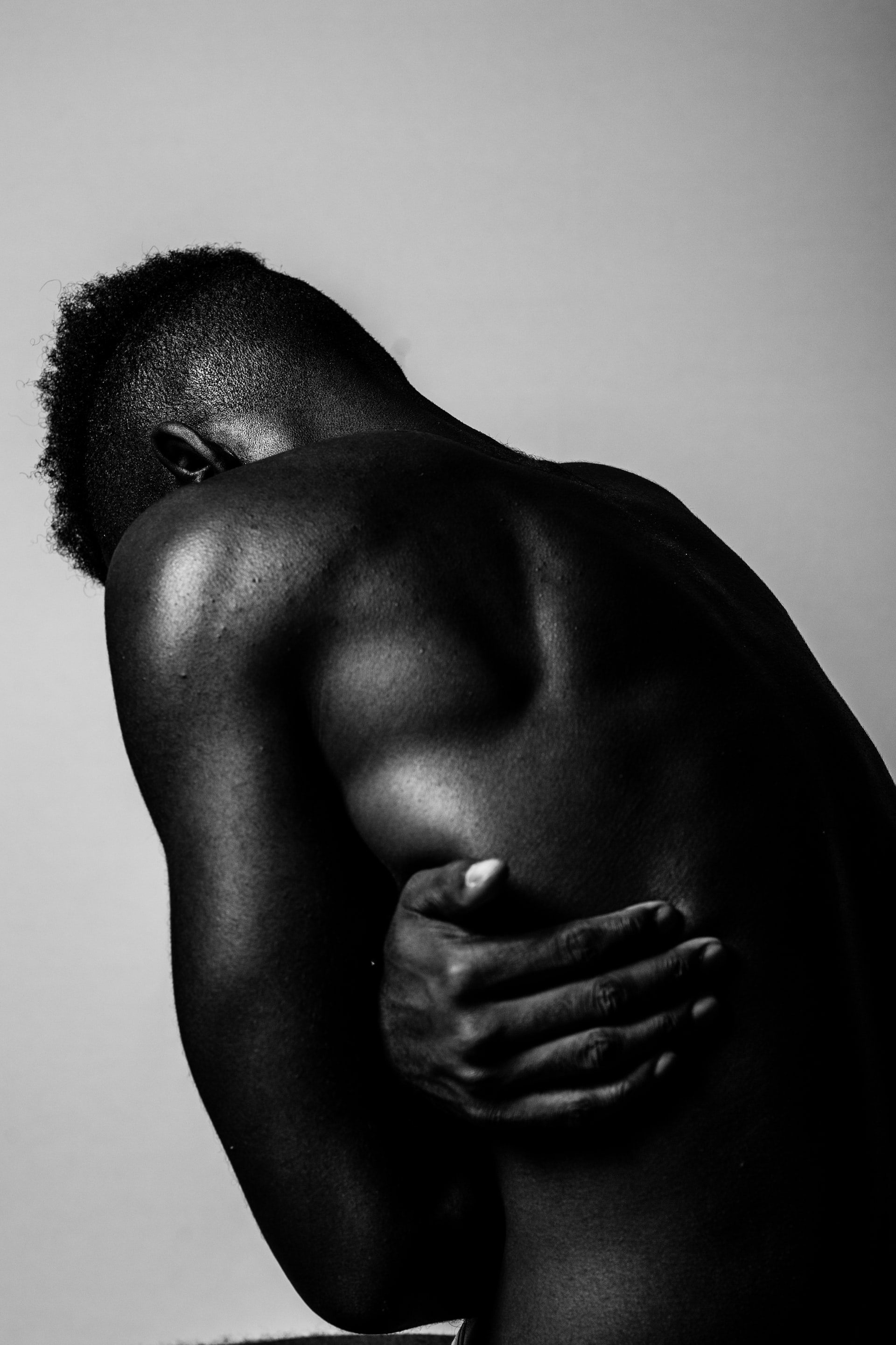 A naked blackman has his hand on his right side abdomen with pain