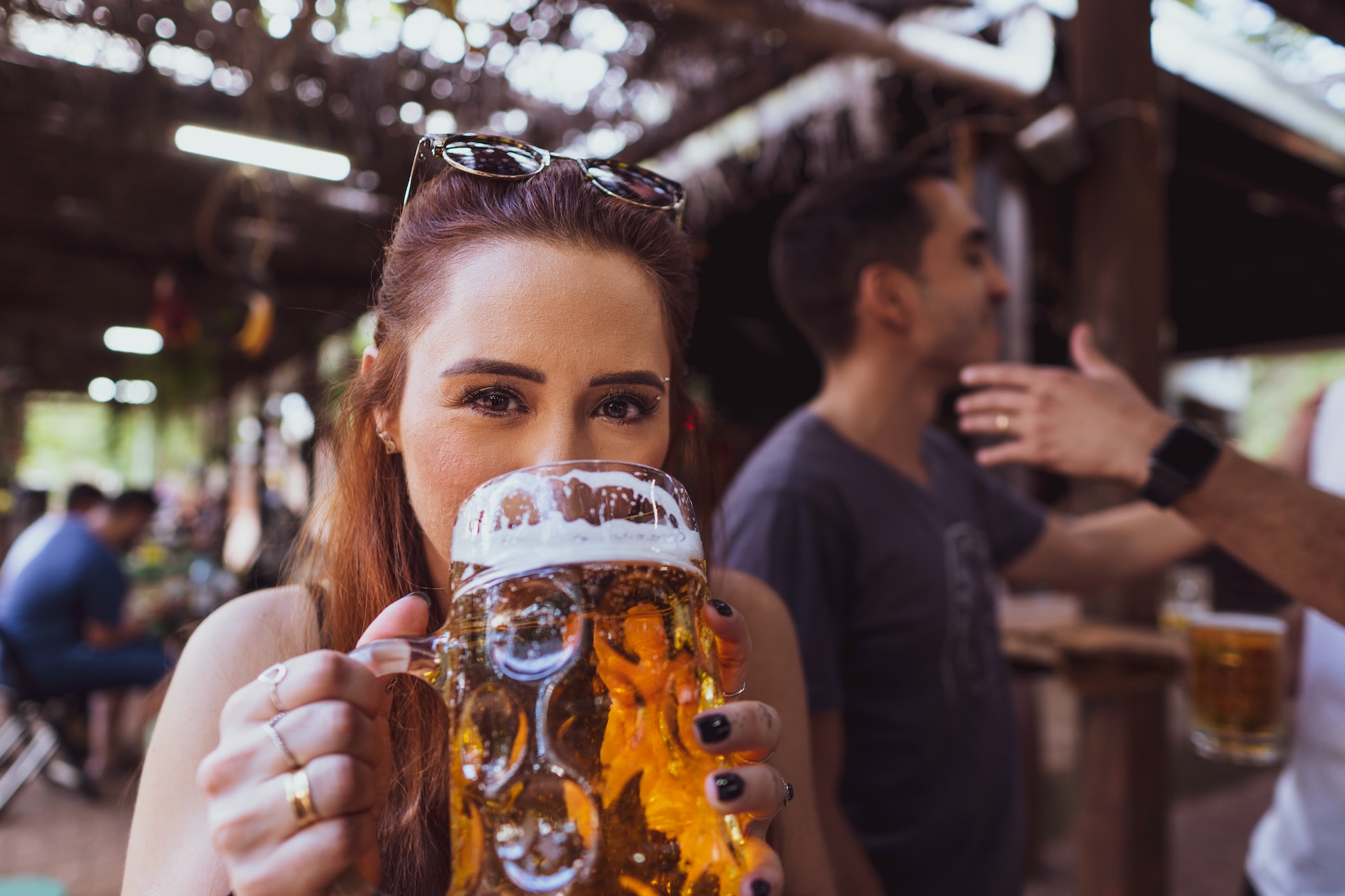 A woman in a pub holding a mug of non-alcoholic beer with both hands and drinking from it