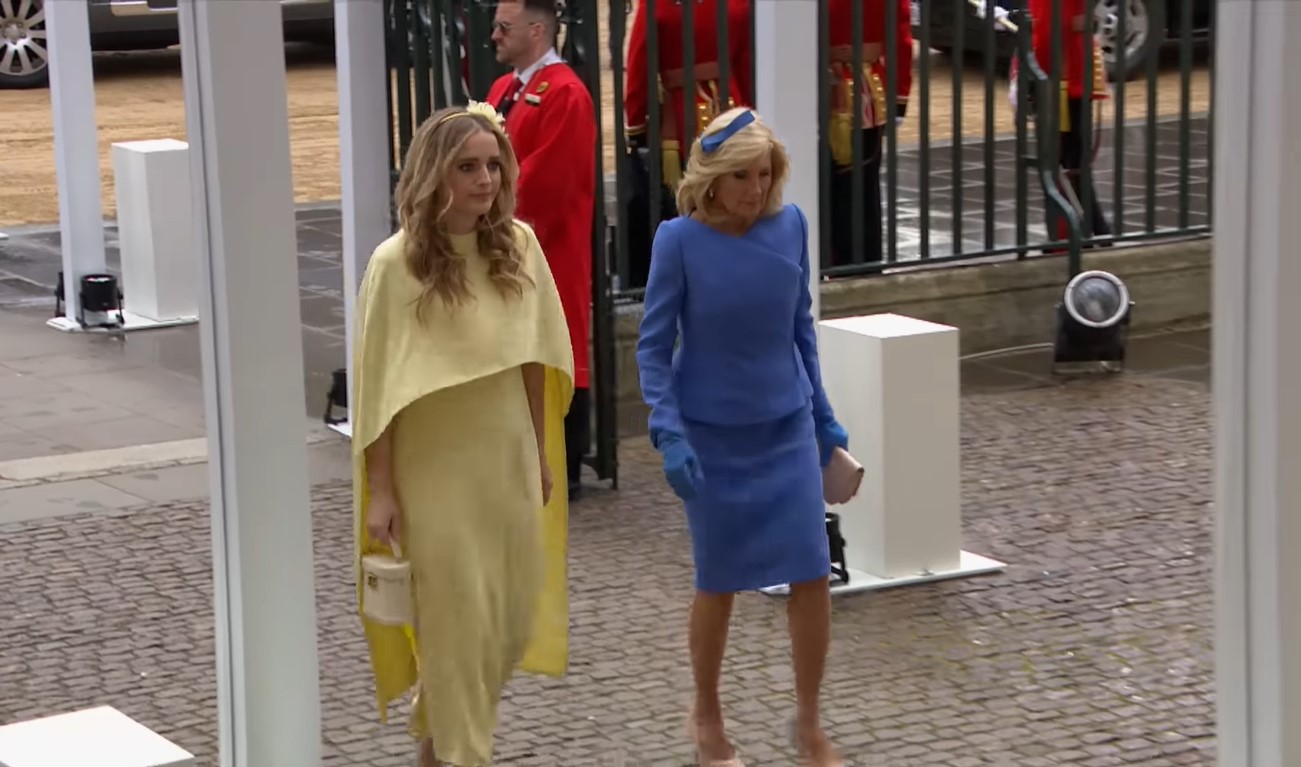 U.S. First Lady Jill Biden in periwinkle skirt suit and female granddaughter in pale yellow cape dress