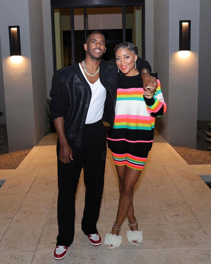 Chris Paul in tucked in white shirt under a black jacket and Jada Crawley in striped knitted dress