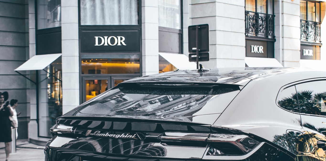 A black Lamborghini parked across a Christian Dior store
