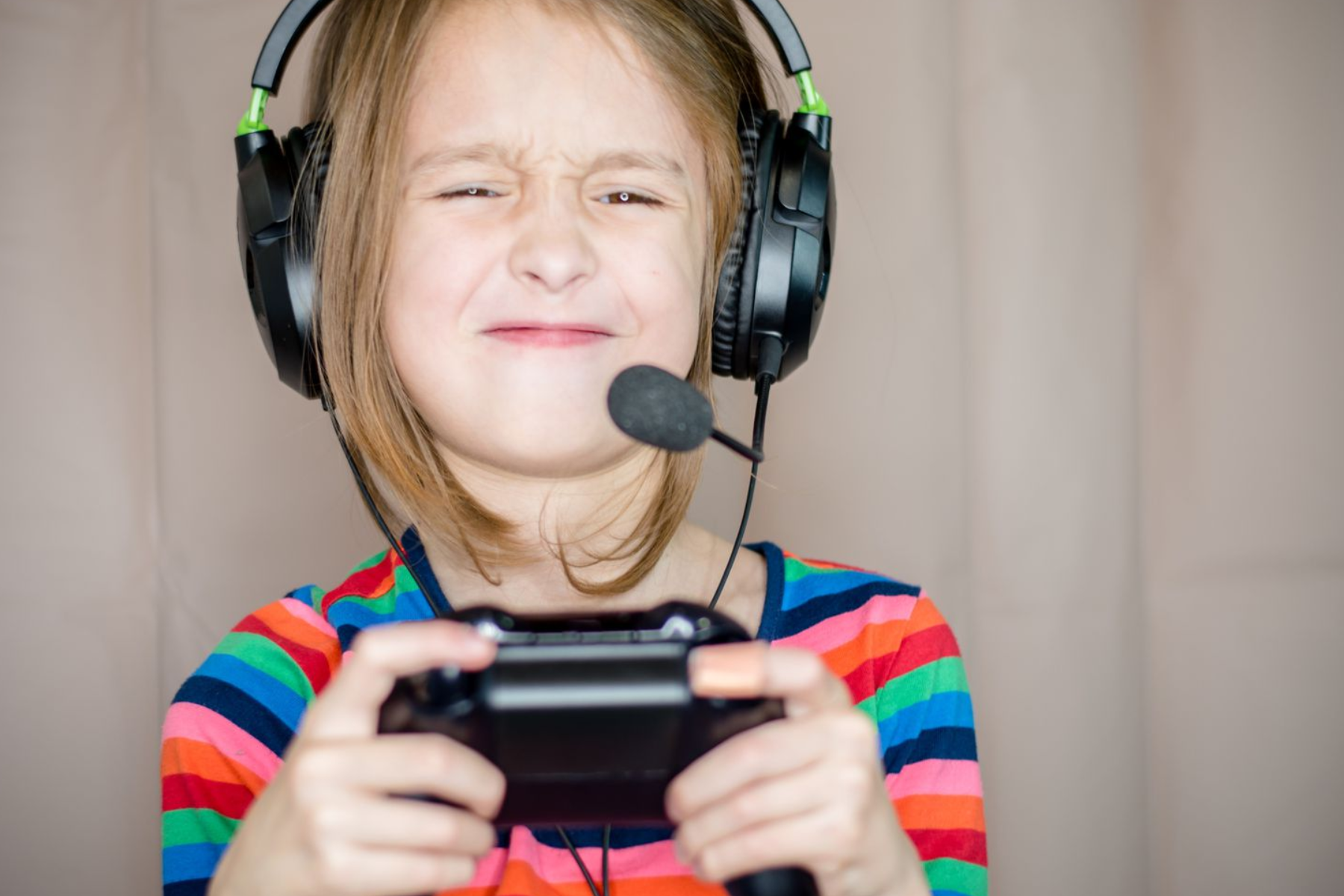 A young girl is seen playing an Xbox One while wearing regular mic headphones