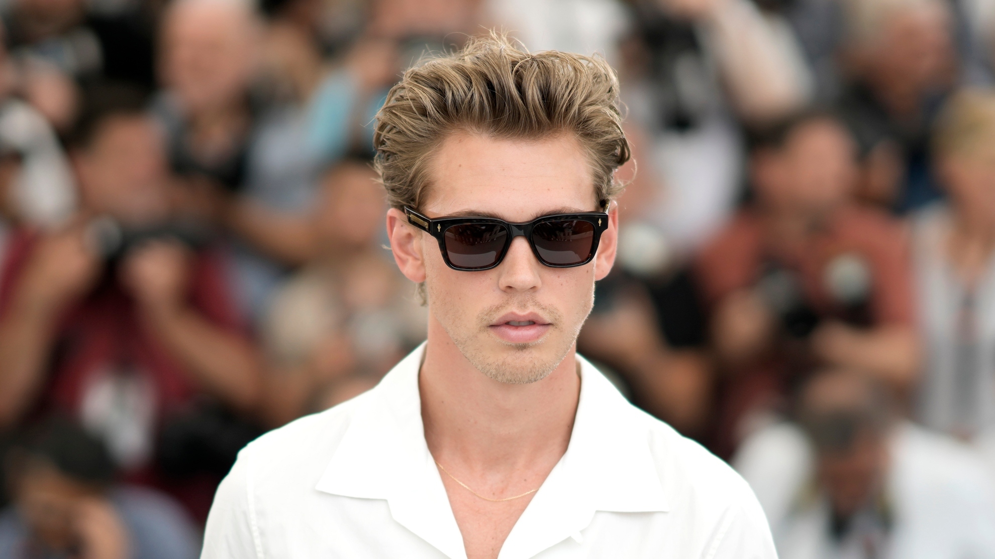 Austin Butler wearing a  whte polo shirt and black sunglasses